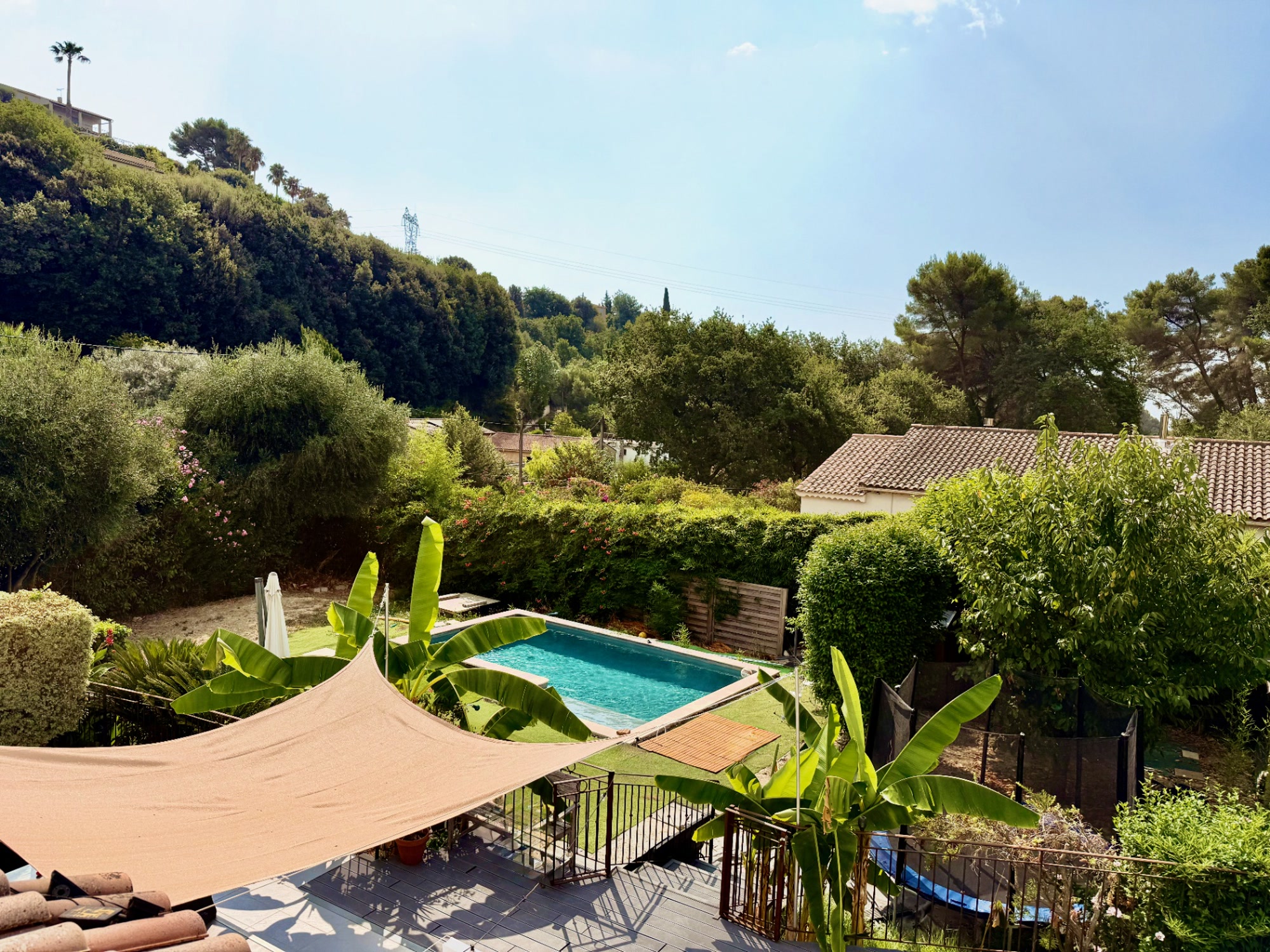 Vue d'ensemble du jardin et de la piscine depuis la terrasse du 2 pièces